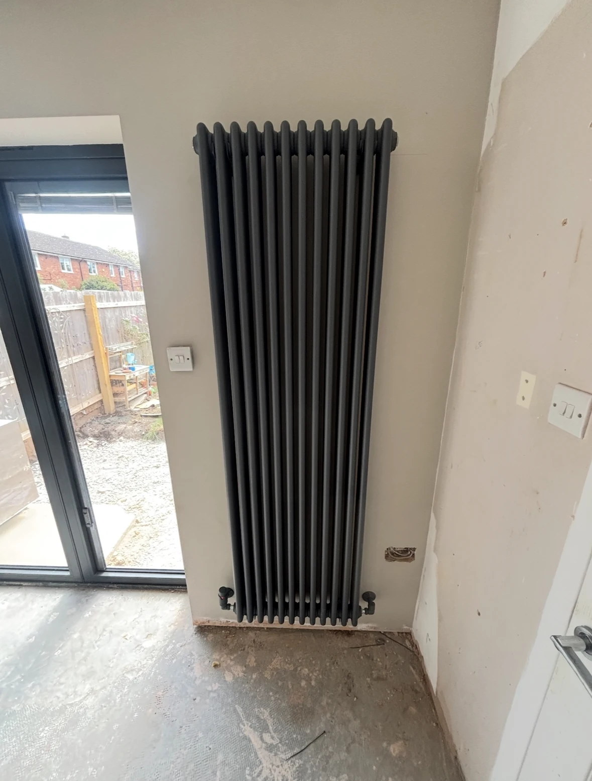 Tall vertical radiator fitted beside patio doors